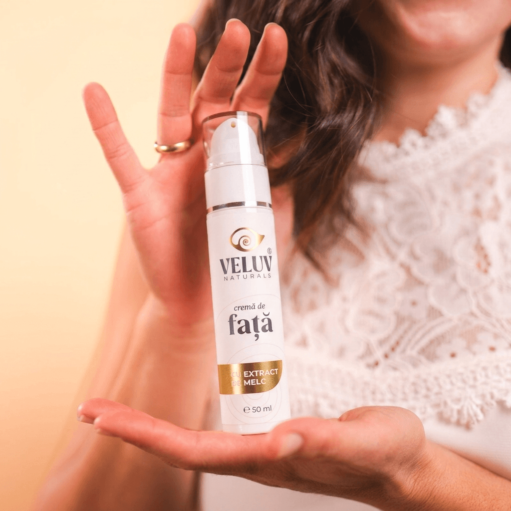 Femeie elegantă ținând flaconul de cremă de față cu extract de melc Veluv Naturals 50ml